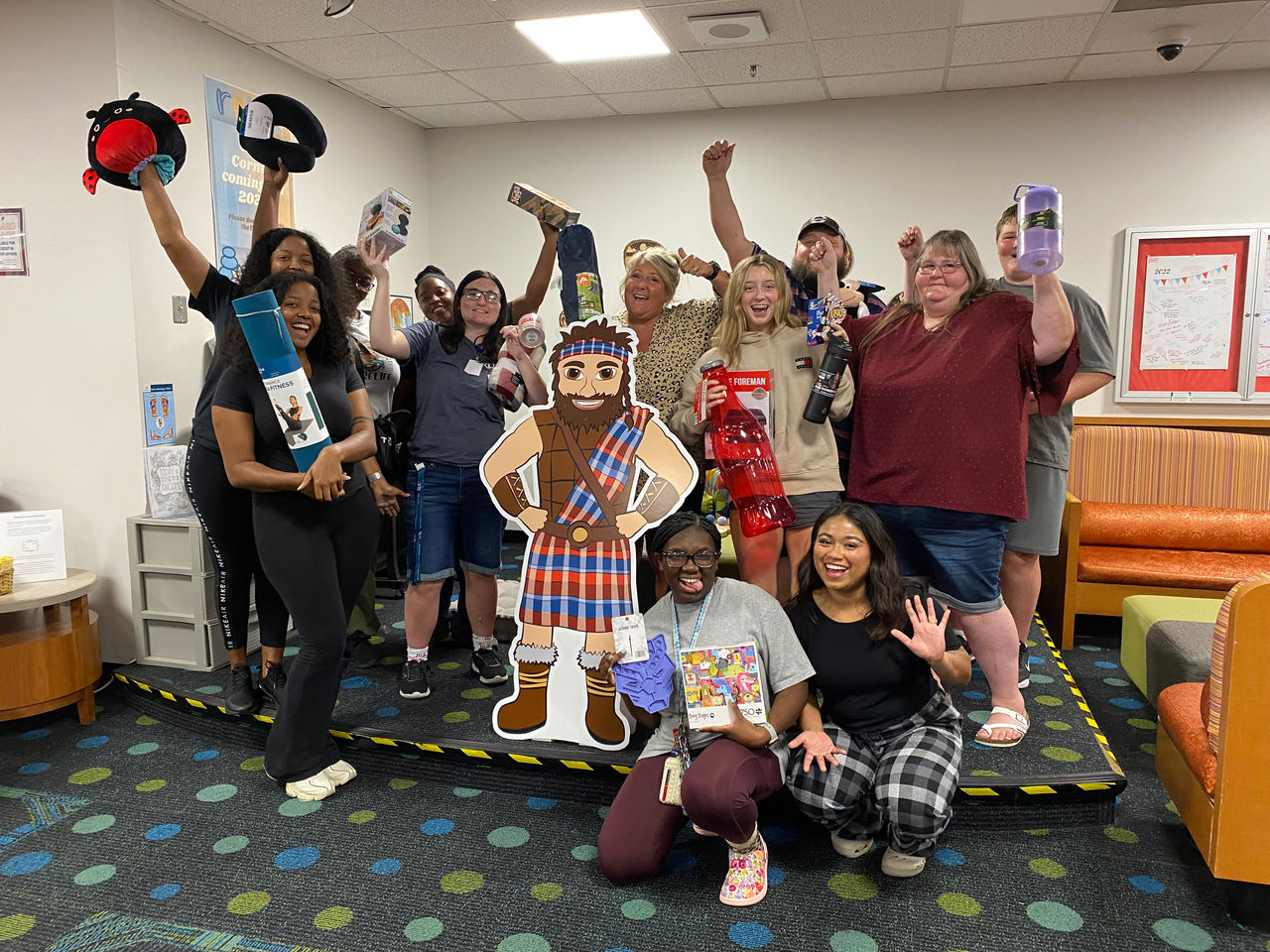 Group of people celebrate with a cut out Highlander and Radford prizes.