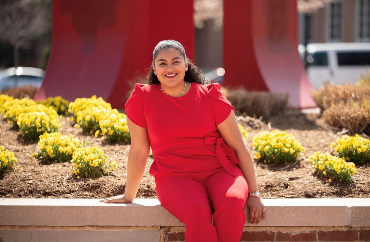 Emily J. Martinez smiling in front of the Heth Clocks on a sunny day!